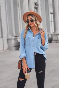 Chic woman wearing a light blue denim shirt and black ripped jeans in urban street setting