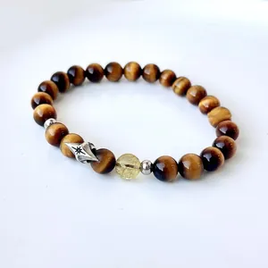 Close-up of yellow tiger eye and rutilated quartz bracelet with silver star charm.