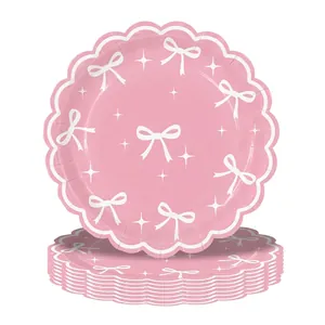 Dettaglio dei piatti di carta rosa smerlati con motivi a fiocco bianco e stelle decorative
