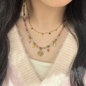 Macro detail of a layered colorful beaded necklace with sun and star charms on model