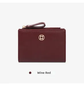 Close-up of a wine red minimalist bifold women's wallet featuring a gold metal emblem.