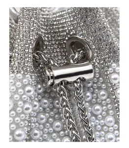 Macro shot of silver evening bag featuring dense rhinestones, pearls and metal drawstring.