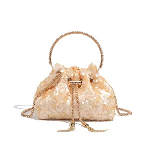 Detail view of champagne sequin bucket evening bag with rhinestone handle and tassel.