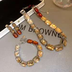 Close-up of champagne and amber rectangular stone jewelry set on grey background