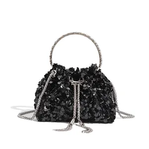Close-up of a black sequined evening bag with a silver circular handle and tassels.