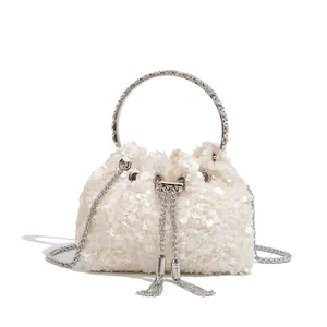 Detail of sequined white evening bucket bag with crystal ring handle and tassels.