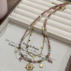 Elegant layered beaded necklace featuring sun and star pendants displayed on jewelry tray