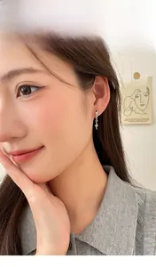 Detailed close-up of a model wearing sparkling silver lightning bolt hoop earrings