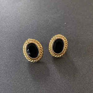 Detailed view of vintage oval gold earrings featuring a faceted black gemstone inlay.