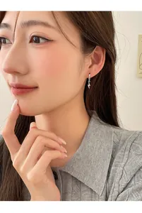 Close-up view of a silver lightning bolt earring with rhinestones on a female model.