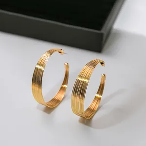 Gros plan de boucles d'oreilles créoles texturées dorées à plusieurs fils en forme de C