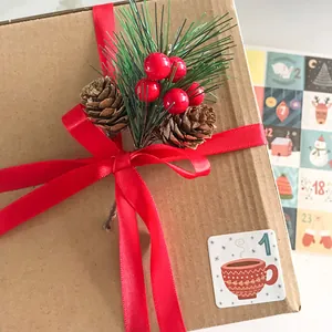 Coffret cadeau de Noël décoré avec des aiguilles de pin, cônes, baies rouges et ruban