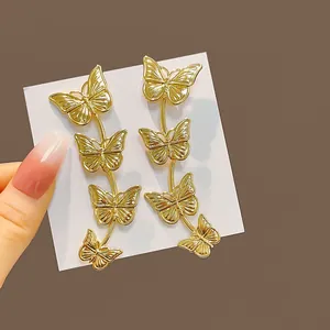 Vue détaillée de longues boucles d'oreilles papillon dorées sur carte de bijouterie