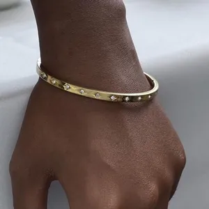 Minimalist gold-plated stainless steel bangle with zircon stones on model's wrist