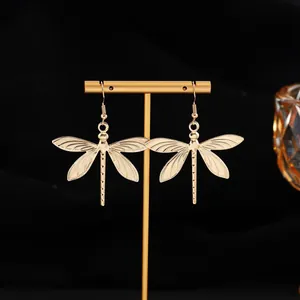 Vue détaillée de boucles d'oreilles libellules dorées avec des ailes texturées