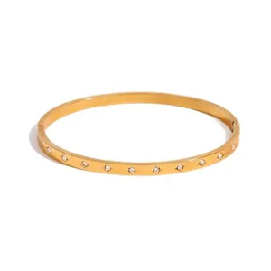 Elegant minimalist gold stainless steel bangle featuring embedded sparkling zirconia stones.