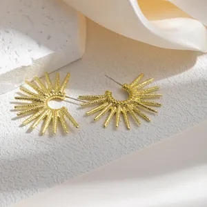 Gros plan détaillé de boucles d'oreilles créoles dorées avec un motif soleil rétro