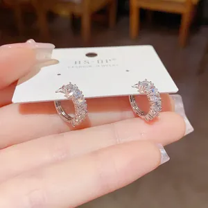 Detailed macro view of sparkling cubic zirconia paved silver huggie hoop earrings on card