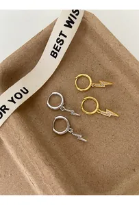 Detailed view of pavé-set gold and silver lightning bolt hoop earrings in a gift tray.