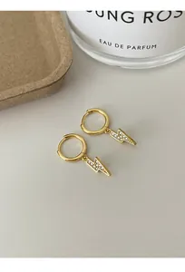Close-up of elegant gold lightning bolt hoop earrings with sparkling micro rhinestones.