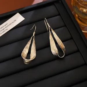 Vue détaillée des boucles d'oreilles pendantes dorées irrégulières sur support noir
