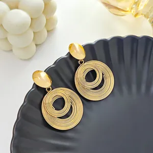 Détail de boucles d'oreilles créoles spirales dorées multicouches sur un plateau noir