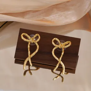 Gros plan d'élégantes boucles d'oreilles nœud dorées avec texture vintage irrégulière