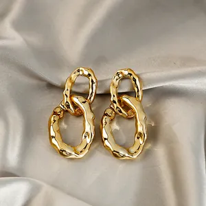 Gros plan de boucles d'oreilles créoles dorées irrégulières sur fond de soie élégant