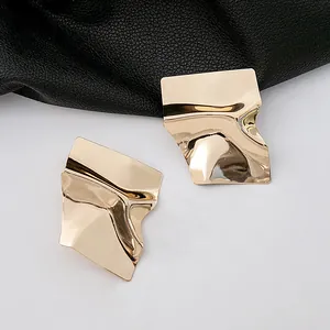 Vue détaillée de boucles d'oreilles irrégulières en métal plaqué or à texture froissée