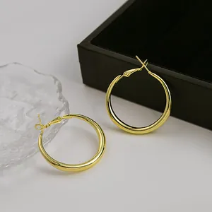Détail de boucles d'oreilles créoles dorées élégantes au fini métal brillant