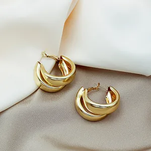 Gros plan de boucles d'oreilles créoles triples dorées au fini métallique poli.