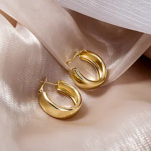 Vue rapprochée détaillée de boucles d'oreilles créoles dorées sur fond de soie champagne luxe.