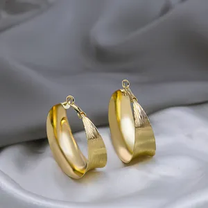 Gros plan de boucles d'oreilles créoles dorées irrégulières avec fini texturé