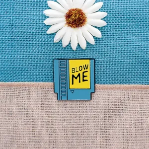 Retro game cartridge enamel pin with Blow Me text on fabric background