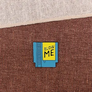 Macro view of a retro game cartridge enamel pin featuring 'Blow Me' text.
