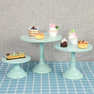Mint green tiered cake stands for dessert display, shown in a rustic table setting.
