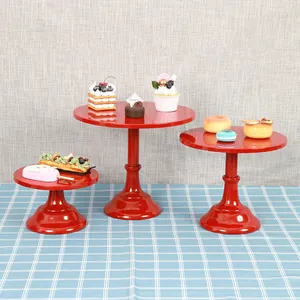 Three red pedestal cake stands in different sizes for dessert table display