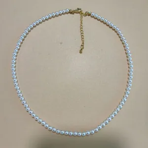 Circular white pearl necklace with gold-toned clasp and extender chain.