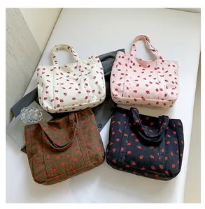 Macro detail view of four colorful corduroy tote bags with cute strawberry prints.