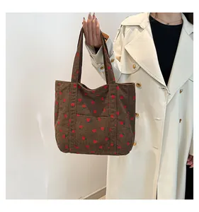 Detailed view of brown corduroy strawberry embroidered tote bag with top handles