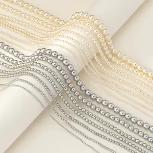 Macro detail of various sizes of cream and silver pearl necklaces on a white display