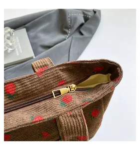 Macro detail of corduroy strawberry tote bag showing zipper and fabric texture