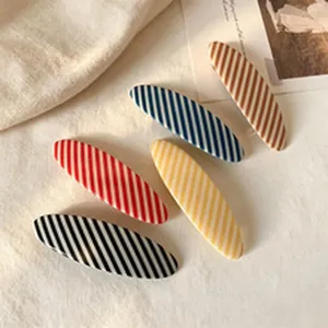 Macro detail of various colorful diagonal striped duckbill hair clips on linen background