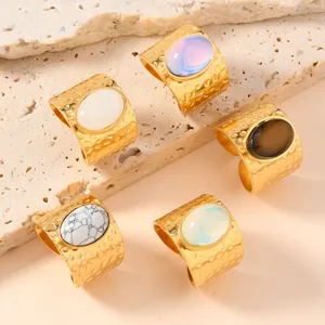Detail of gold-plated stainless steel open rings with oval natural stones and hammered texture