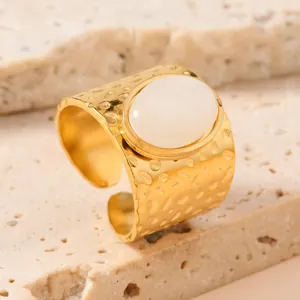 Detailed view of gold stainless steel ring featuring white oval stone and hammered texture