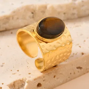 Detailed view of gold stainless steel ring with hammered texture and oval brown stone