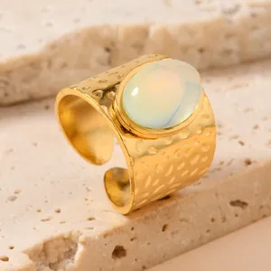 Close-up detail of a hammered gold stainless steel open ring with an oval natural stone gem