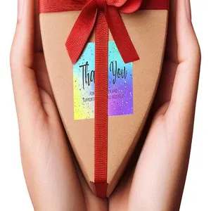 Detailed view of a colorful Thank You card on a heart-shaped gift box held by hands.