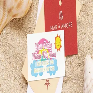 Detailed close-up of a colorful thank you card with a rainbow and sun design resting on beach sand