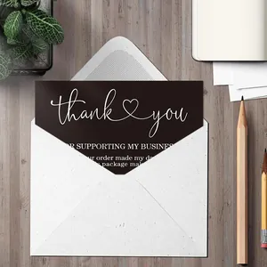 Close-up of black thank you card with white script in a white envelope